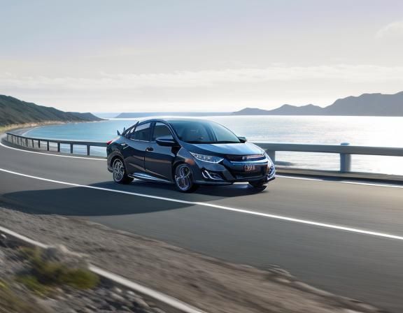 A stunning Honda Civic driving on the road by the sea.